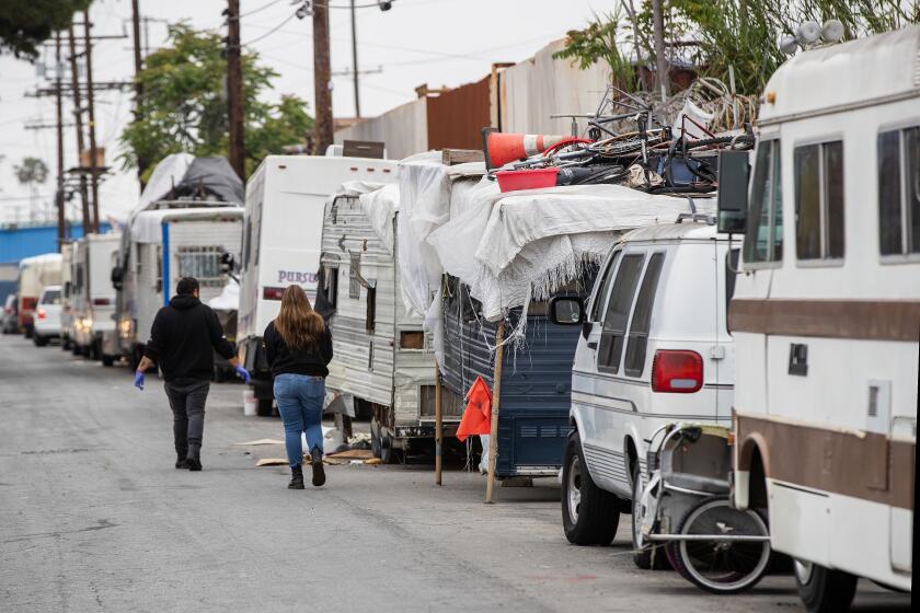 Los Angeles, CA - May 19: Carlos Vargas, left, and Paulina Rubio, members of the harm reduction team from Homeless Outreach Program Integrated Care Systems [HOPICS], a leading homeless services and housing agency, look for drug addicts to help and pass out supplies at a homeless RV encampment along 77th St. in South Los Angeles Friday, May 19, 2023. The team hands out syringes, fentanyl test strips, overdose reversal nose spray and medication to prevent overdoses, infection and disease transmission, including the HIV virus. Fenanyl is particularly insidious because it can be found in all other drugs, especially meth and heroin. The handouts are also meant to reduce infection through broken pipes, which can cut users mouths and open them to infection. . (Allen J. Schaben / Los Angeles Times)