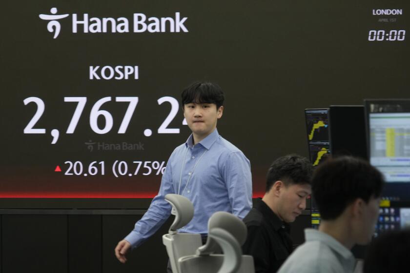 A currency trader walks by the screen showing the Korea Composite Stock Price Index (KOSPI) at the foreign exchange dealing room of the KEB Hana Bank headquarters in Seoul, South Korea, Monday, April 1, 2024. Asian shares were mixed Monday, with Shanghai gaining 1% after surveys showed improvements in manufacturing conditions in China. (AP Photo/Ahn Young-joon)