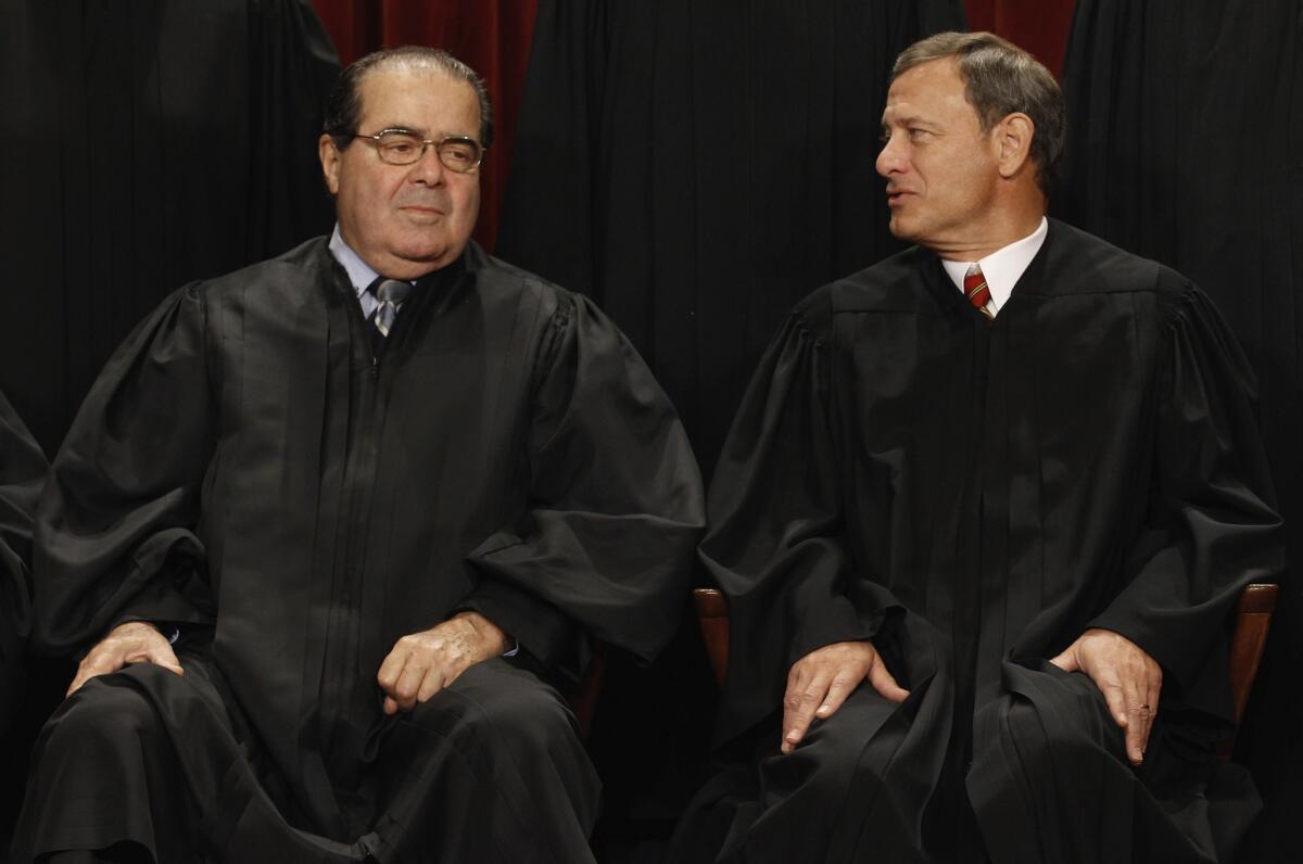 Supreme Court Justice Antonin Scalia, left, and Chief Justice John G. Roberts Jr. wait for an official court portrait to be taken in 2010.