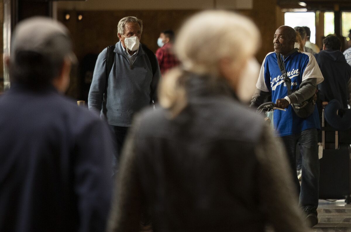 Masked and unmasked visitors walk through Union Station in Los Angeles