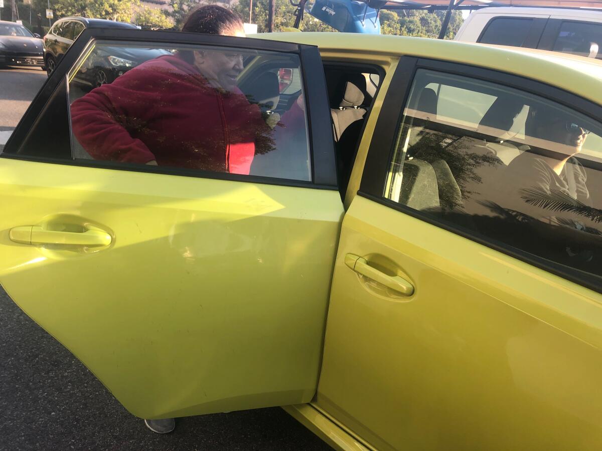 Carmen Solano gets in the back of an Uber car after finding out the neighborhood where she works had been evacuated because of the Getty fire.