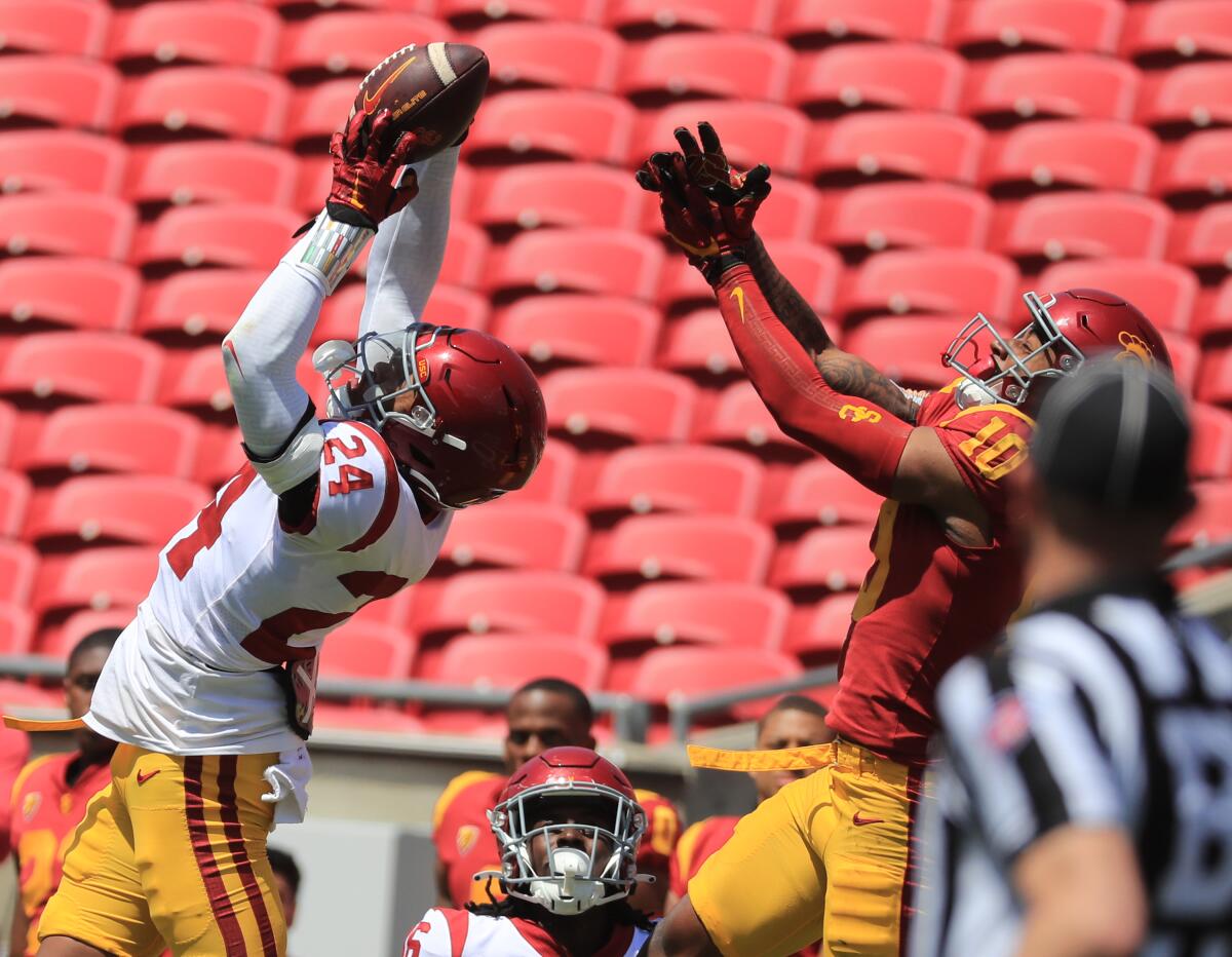 USC defensive back Christian Pierce makes an interception in front of wide receiver Kyron Hudson during the spring game.