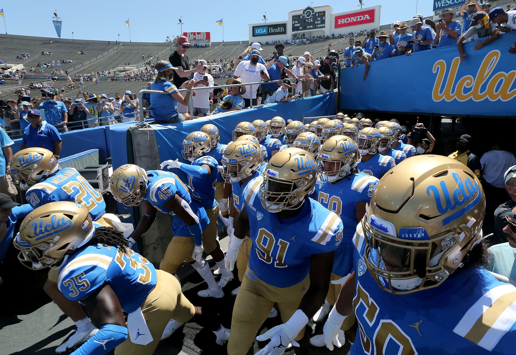 UCLA players take the field at the Rose Bowl for their season opener against Hawaii.