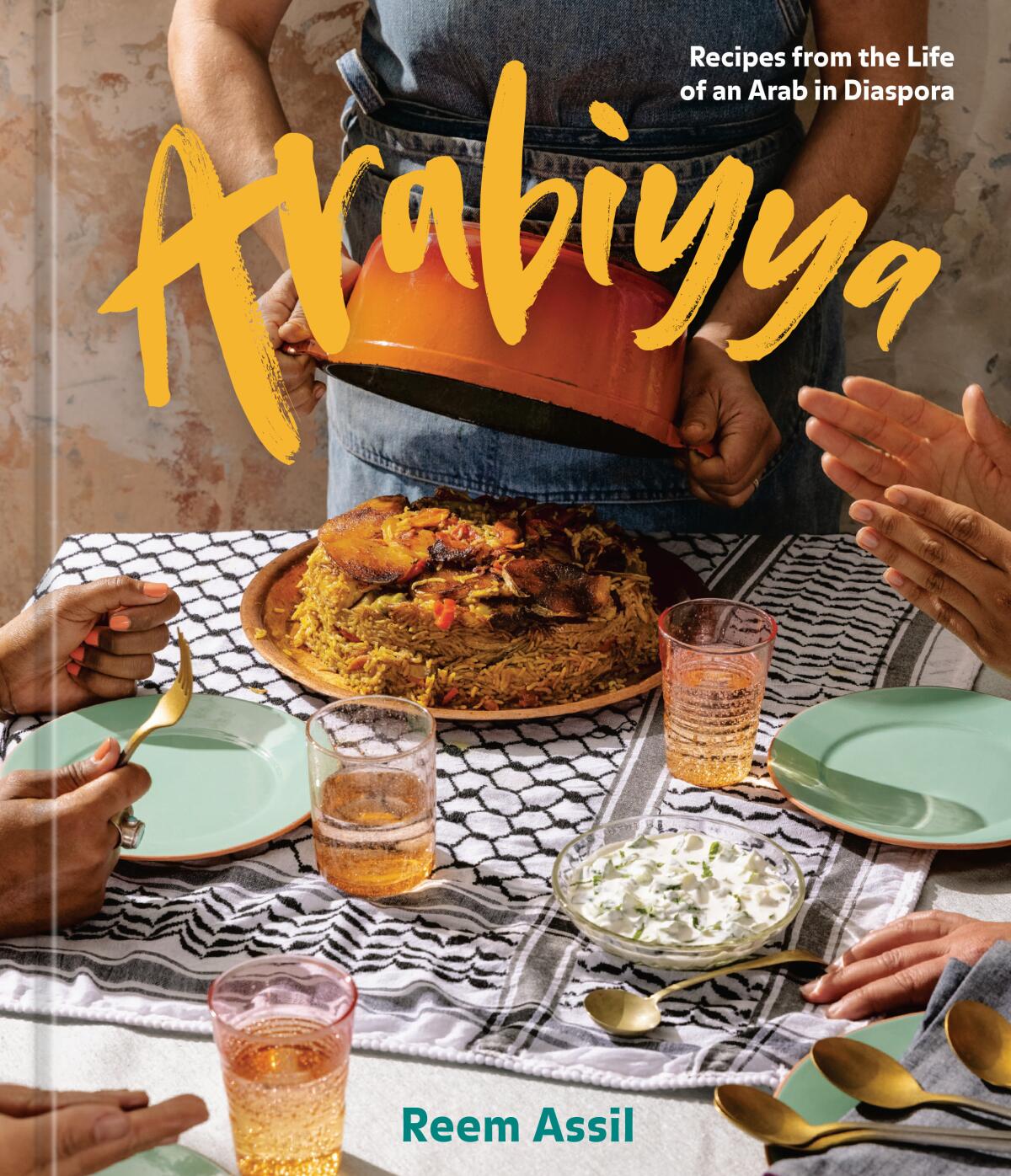 The cover of a book shows a close-up of plates and hands and a main dish on a dining table.