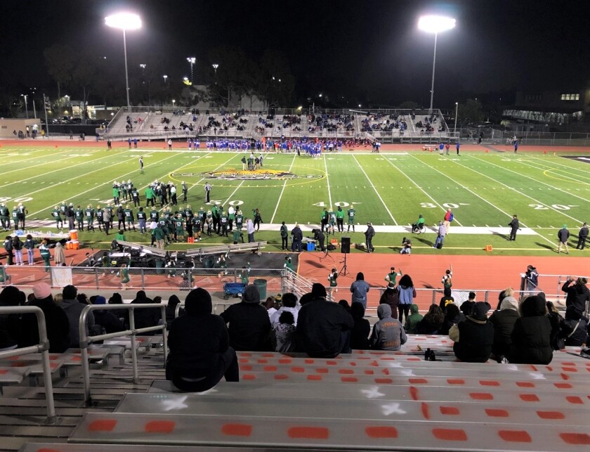 Fans scattered in stands overlooking football field.