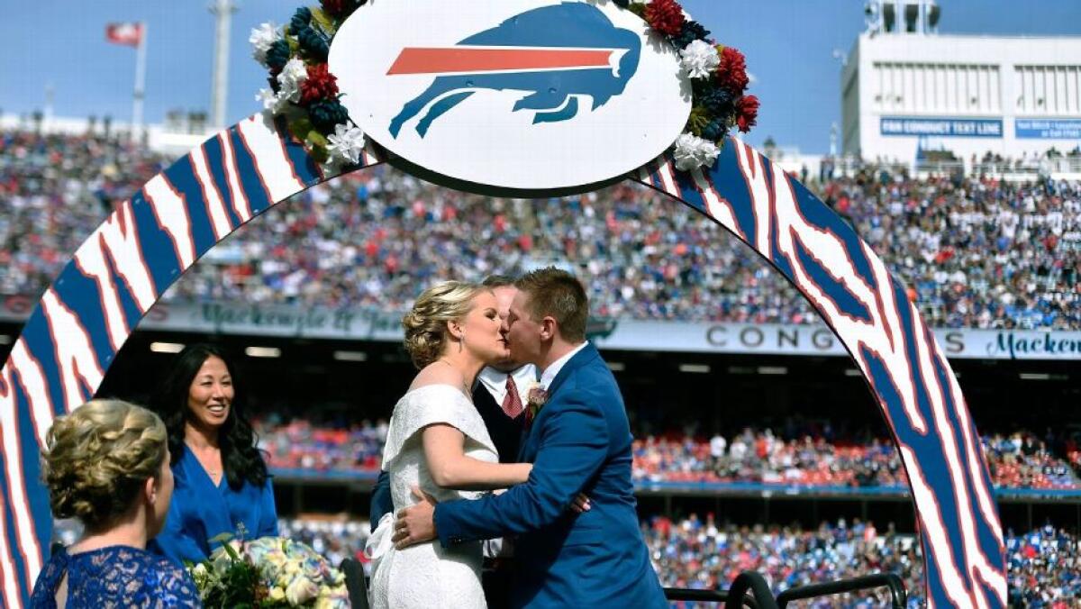 Mackenzie Park and Jordan Binggeli share a kiss after being married at midfield during halftime.