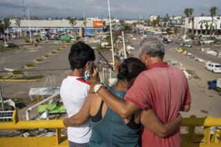 Residents, standing on an overpass, look at damaged caused by Hurricane Otis, in Acapulco, Mexico, Friday, Oct. 27, 2023. (AP Photo/Felix Marquez)