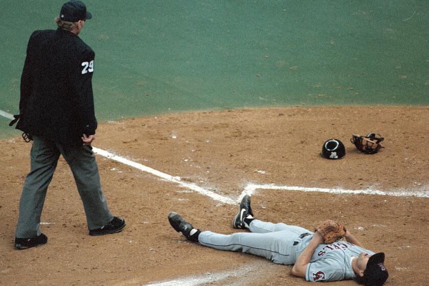 Angels pitcher Mark Langston lies dejected by the umpire at home plate after Mariners infielder Luis Sojo scored on a broken bat double with the bases loaded.