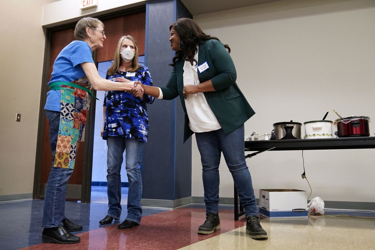 Iowa Democratic gubernatorial candidate Deidre DeJear, right, greets Rebecca Hoeppner, left, and Maddie Anderson, center, at the Story County Democrats Super Soup Fundraiser, Saturday, March 12, 2022, in Nevada, Iowa. (AP Photo/Charlie Neibergall)
