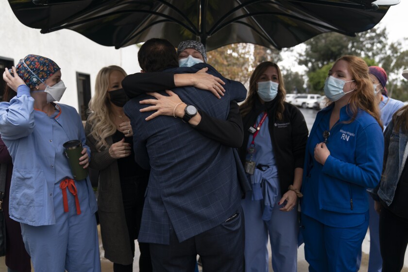 Registered nurse Lisa Lampkin, center, facing camera, hugs her former COVID-19 patient, Brian Patnoe, at Providence Mission Hospital in Mission Viejo, Calif., Thursday, Dec. 9, 2021, as former coronavirus patients and their caregivers gather to celebrate the hospital's 50th anniversary. It was an emotional reunion for the patients and the nurses, respiratory therapists and doctors who saved their lives at a time when little was known about the virus that has since overrun the world. (AP Photo/Jae C. Hong)
