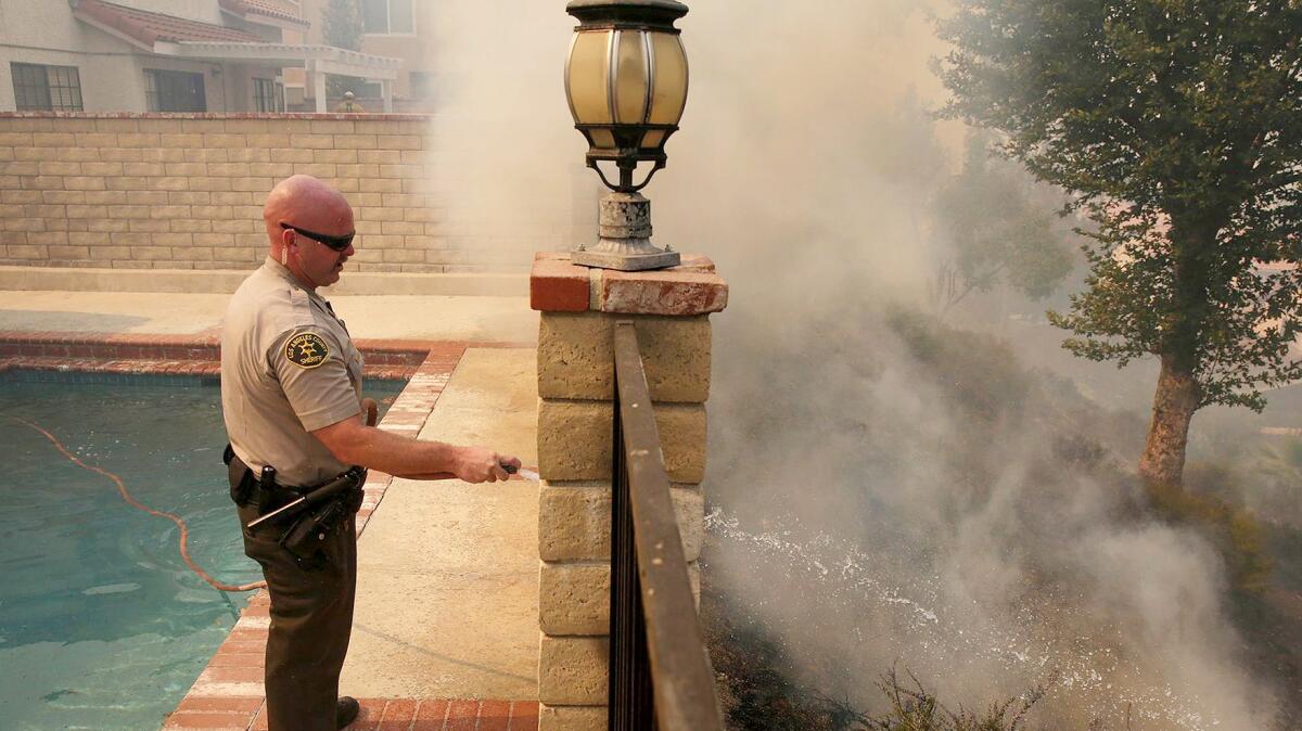 A March 2017 photo of L.A. County Sheriff's Deputy Jason Viger hosing down a hot spot in Newhall.