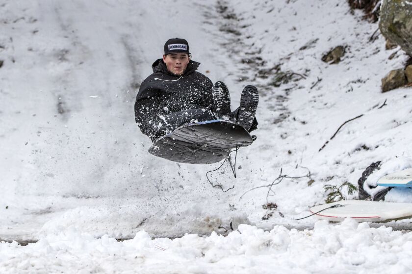 FOREST FALLS, CA - DECEMBER 28, 2021: Matthew Eastman, 15, of Forest Falls sleds off a jump he built at the end of his driveway after Monday's winter stormed blanketed the San Bernardino Mountains on December 28, 2021 in Forest Falls, California.(Gina Ferazzi / Los Angeles Times)