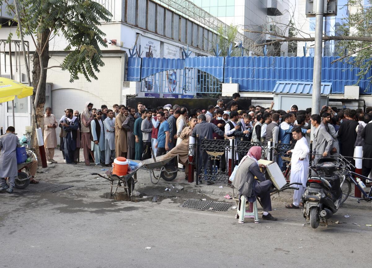 Afganos hacen fila para tratar de retirar dinero frente a un banco de Kabul, Afganistán,