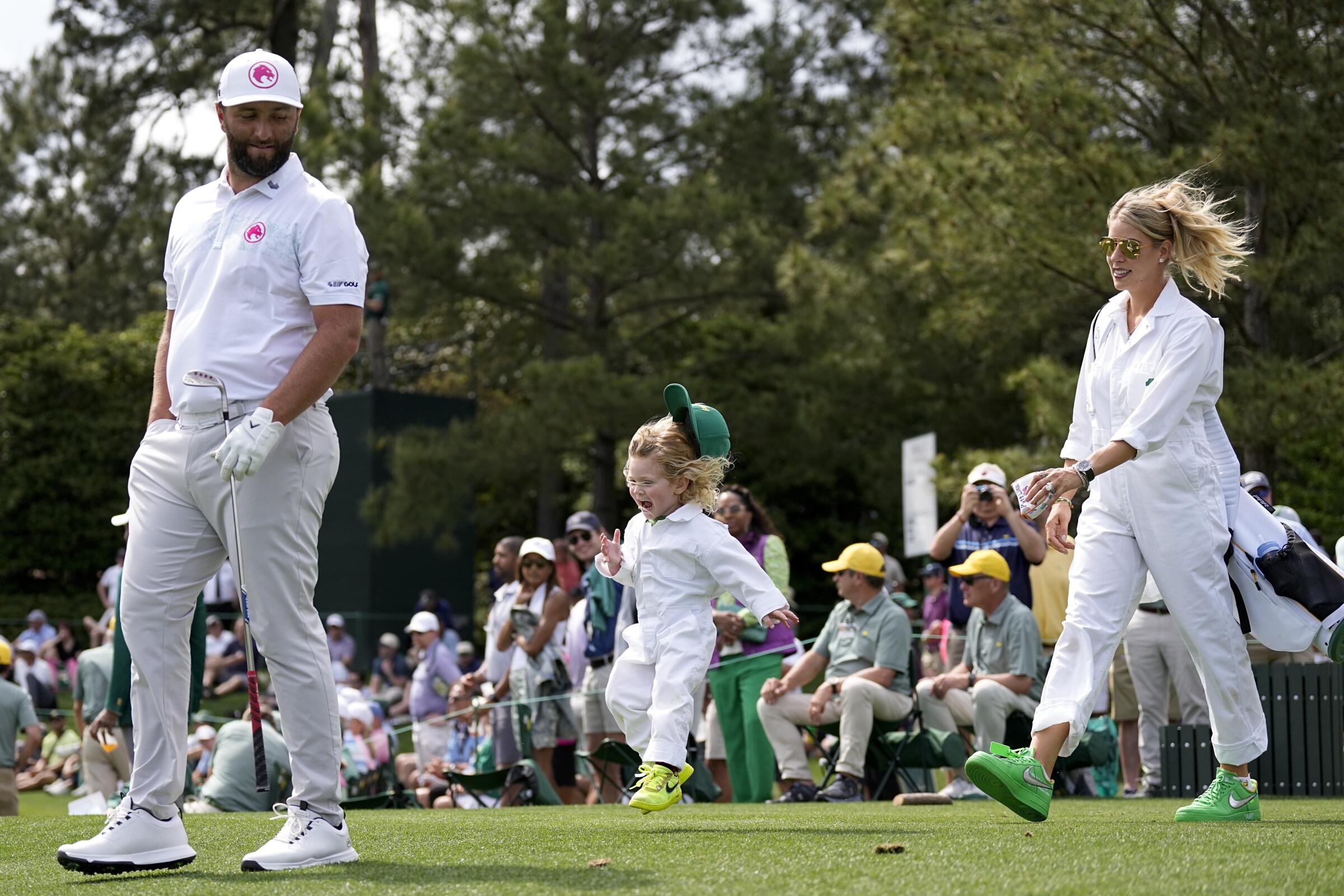 Jon Rahm, of Spain, walks with his wife, Kelley Cahill, and son, Kepa, during the par-3 contest at the Masters.