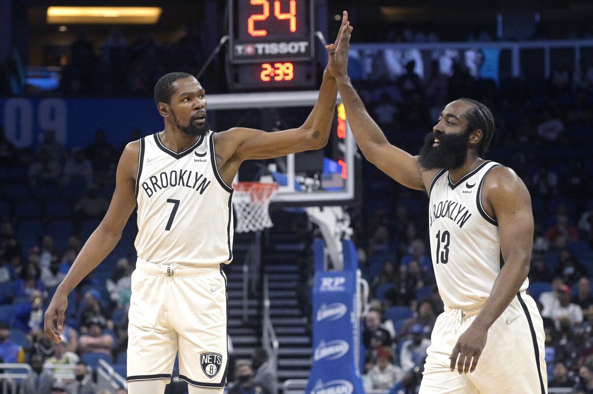 Brooklyn Nets forward Kevin Durant (7) and guard James Harden (13) high-five after a basket during the first half of the team's NBA basketball game against the Orlando Magic, Wednesday, Nov. 10, 2021, in Orlando, Fla. (AP Photo/Phelan M. Ebenhack)