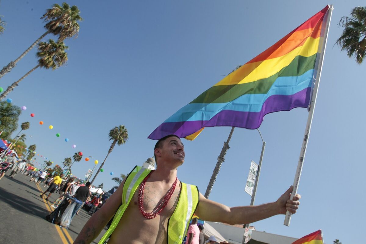 A parade-goer holds up the Pride flag during the seventh annual Pride By the Beach event.