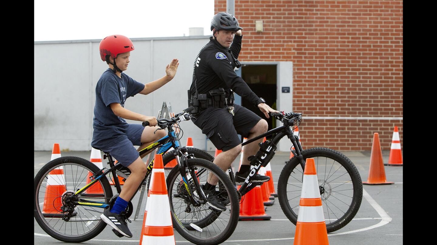 Fourth-grader George Bielen makes a right-turn hand signal as Costa Mesa police Officer Trevor Jones guides him through an obstacle course during Wednesday's Bike Rodeo at Kaiser Elementary School in Costa Mesa.