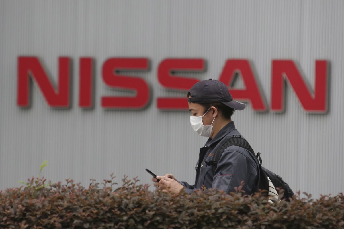 A man walks past the corporate logos at the global headquarters of Nissan Motor Co., Ltd. in Yokohama near Tokyo, Thursday, May 21, 2020. Nissan says it is developing a new way to produce auto parts, highlighting the Japanese automaker’s engineering finesse, even as it struggles to recover from a scandal centered around its former chairman, Carlos Ghosn. (AP Photo/Koji Sasahara)