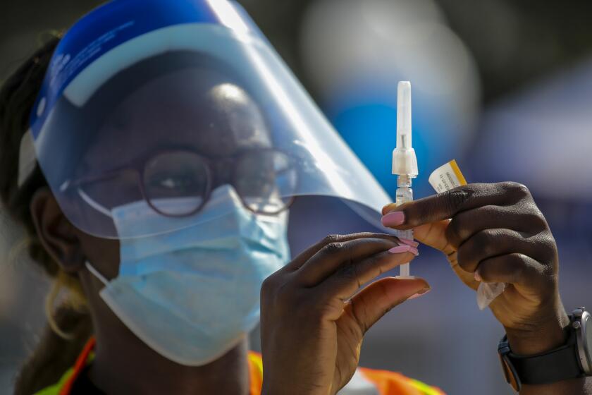 LOS ANGELES, CA - OCTOBER 17: Whitney Fakolade, a student of USC School of Pharmacy, prepares a flu shot for a client at a flu vaccination clinic held by L.A. Care Health Plan, Blue Shield California Promise Health Plan and LA County USC Medical Center at Exposition Park on Saturday, Oct. 17, 2020 in Los Angeles, CA. (Irfan Khan / Los Angeles Times)