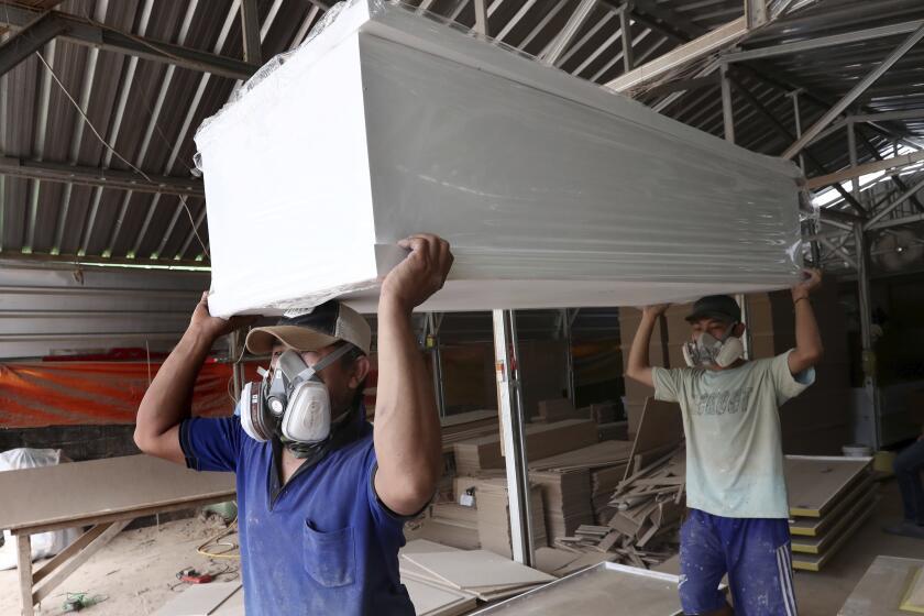 Workers in protective face masks carry coffins built for those who died from the coronavirus at a factory in Serpong, outside Jakarta, Indonesia, Thursday, April 9, 2020. The new coronavirus causes mild or moderate symptoms for most people, but for some, especially older adults and people with existing health problems, it can cause more severe illness or death. (AP Photo/Tatan Syuflana)