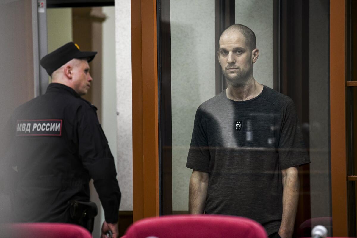 Wall Street Journal reporter Evan Gershkovich stands in a glass cage, listening to the verdict against him.