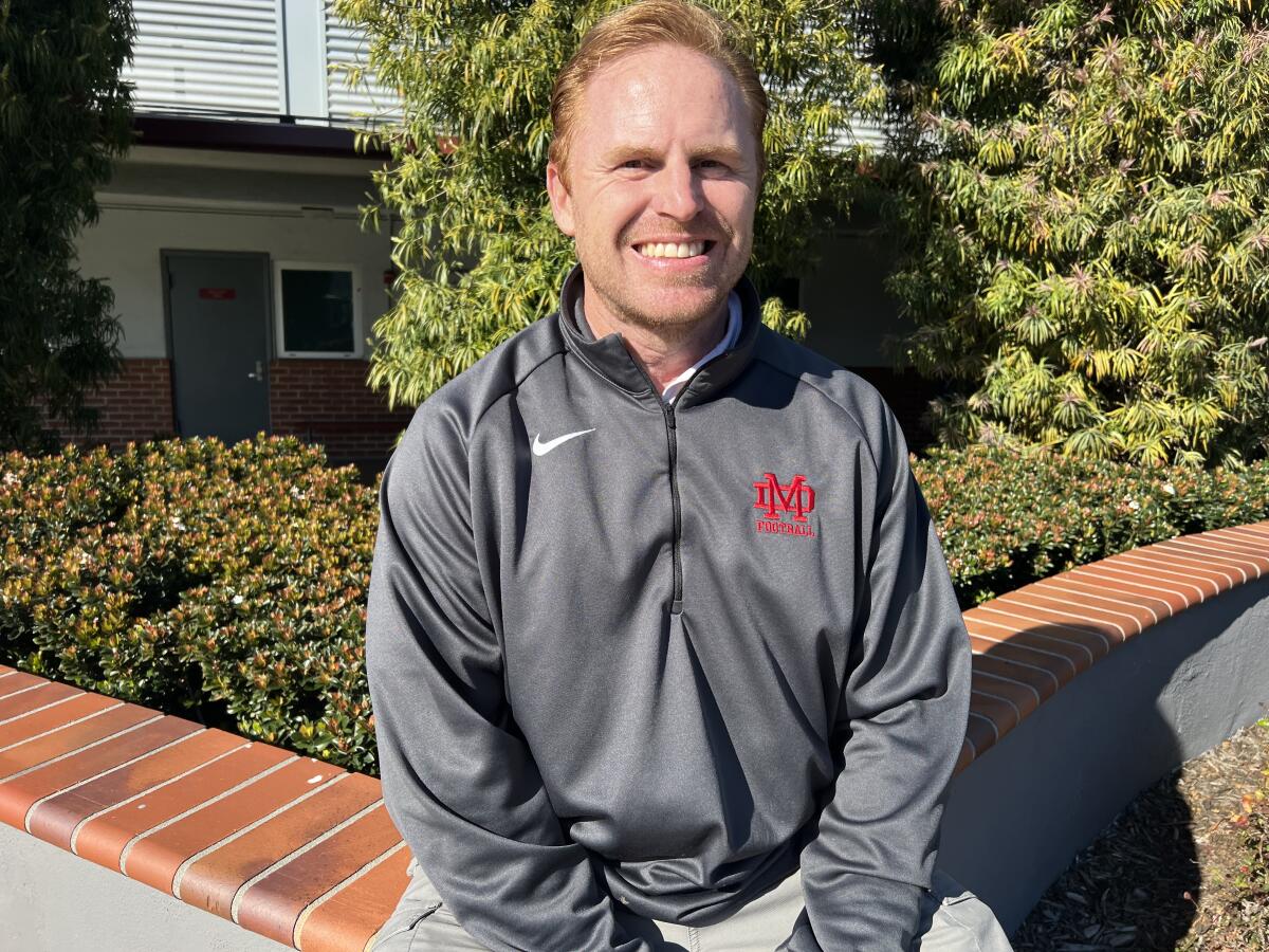 New Mater Dei High head football coach Frank McManus sits and smiles on campus.