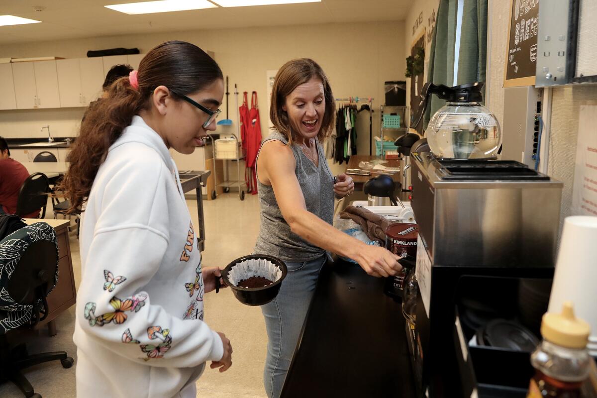 Teacher Courtney Gillett gets senior Hazel Pena started with the coffee machine as they fill orders Friday.