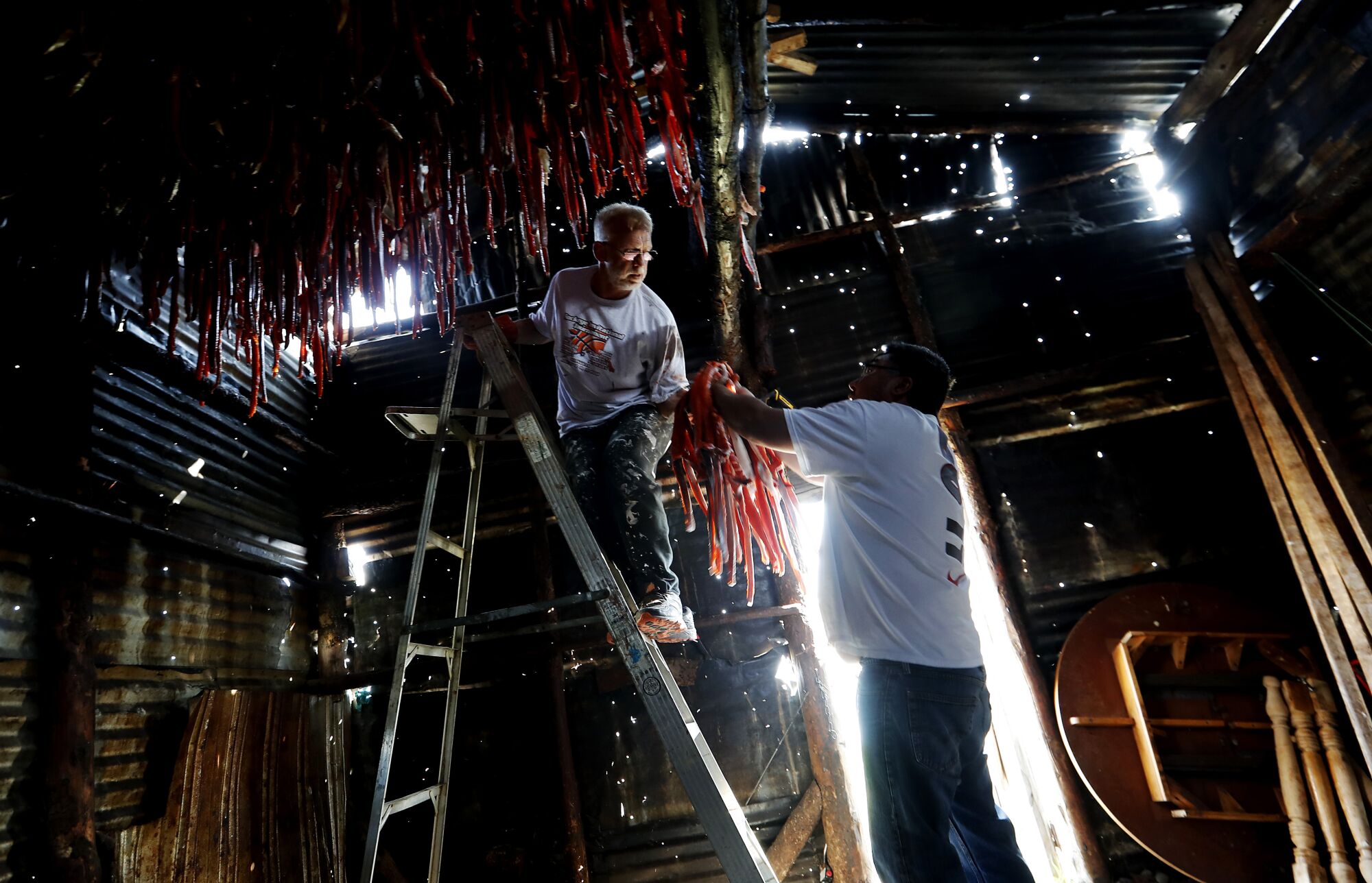 Bob Rychkjovski and Jack Paine hang salmon strips in Newhalen, Alaska.
