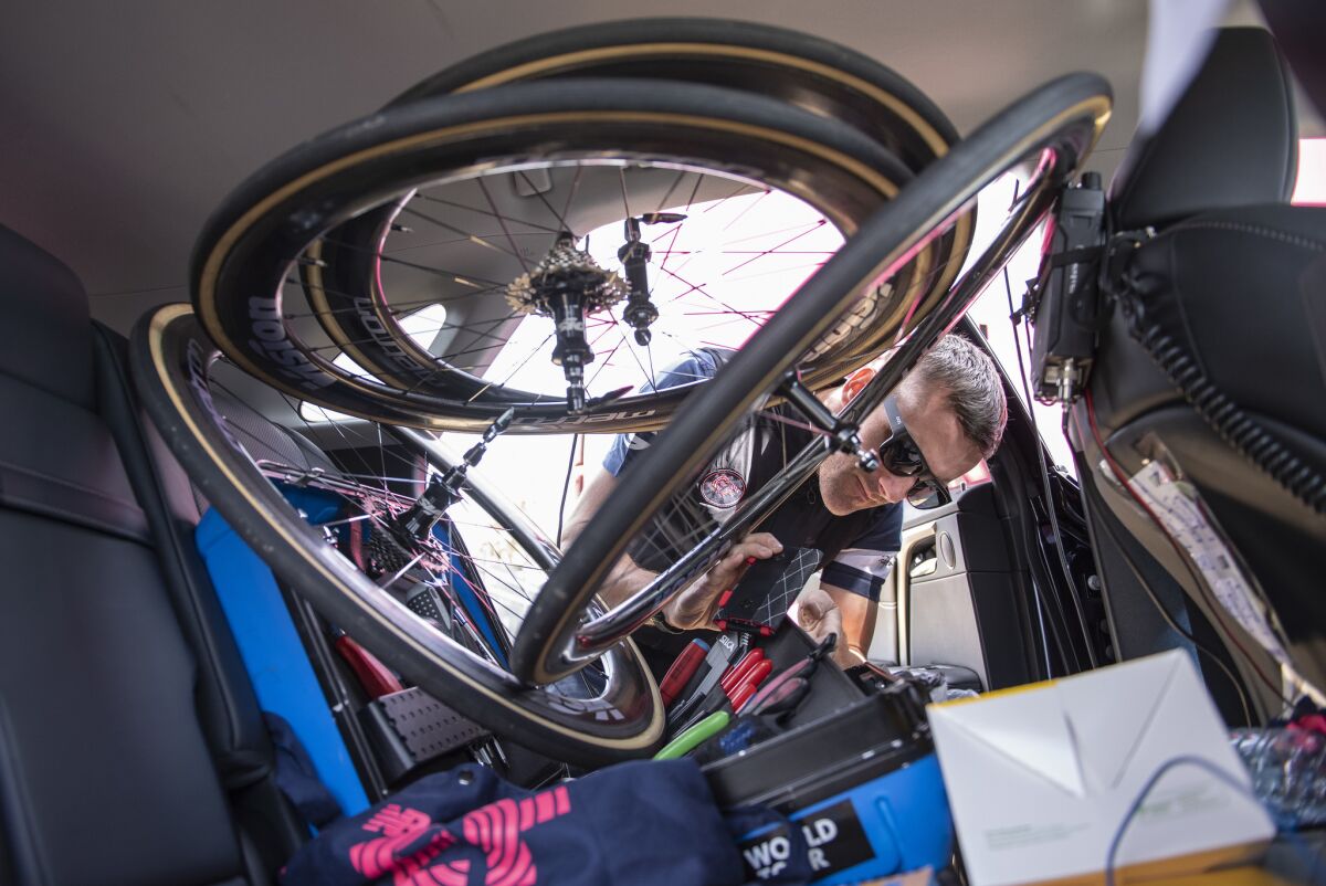 Education First team mechanic Tom Hopper lifts up the stack of spare wheels in the back seat to get a tool from his kit before the start of the third stage of the Amgen Tour of California.