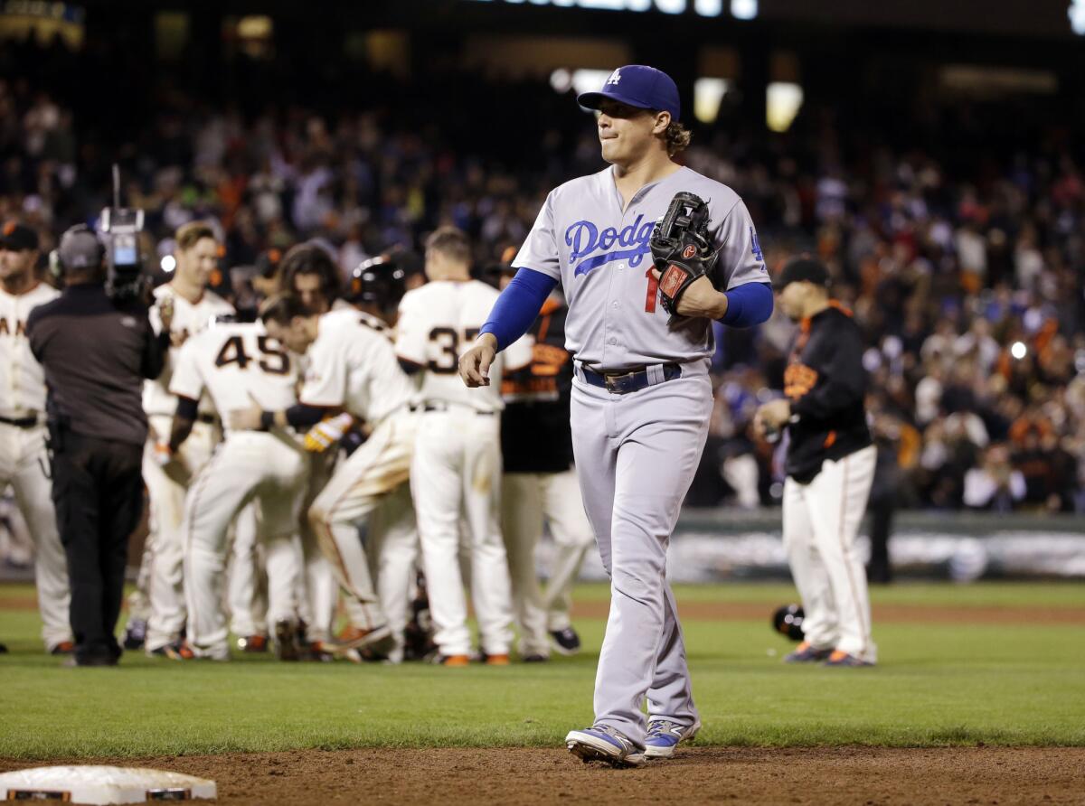 Dodgers' Enrique Hernandez walks off the field as the San Francisco Giants' celebrate a walk-off 3-2 in the 12th inning on Monday night.