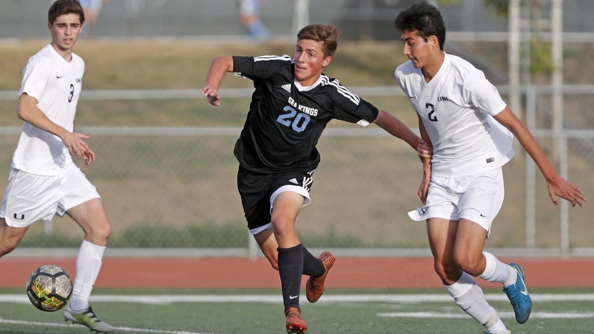 Corona del Mar High's Jennings Torgelson (20) battles for a loose ball with University's Sam Kammerman (2) during the first half of a Pacific Coast League game on Tuesday.