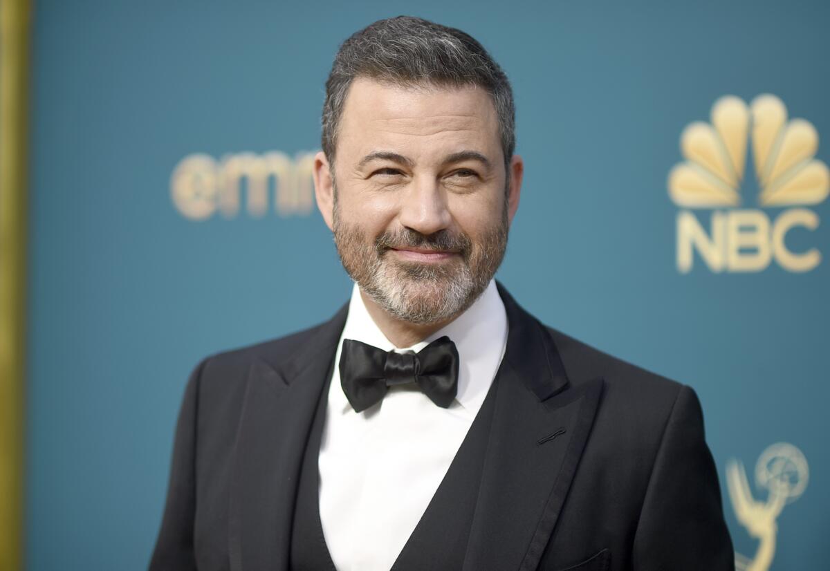 Jimmy Kimmel in a tuxedo posing in front of a turquoise backdrop