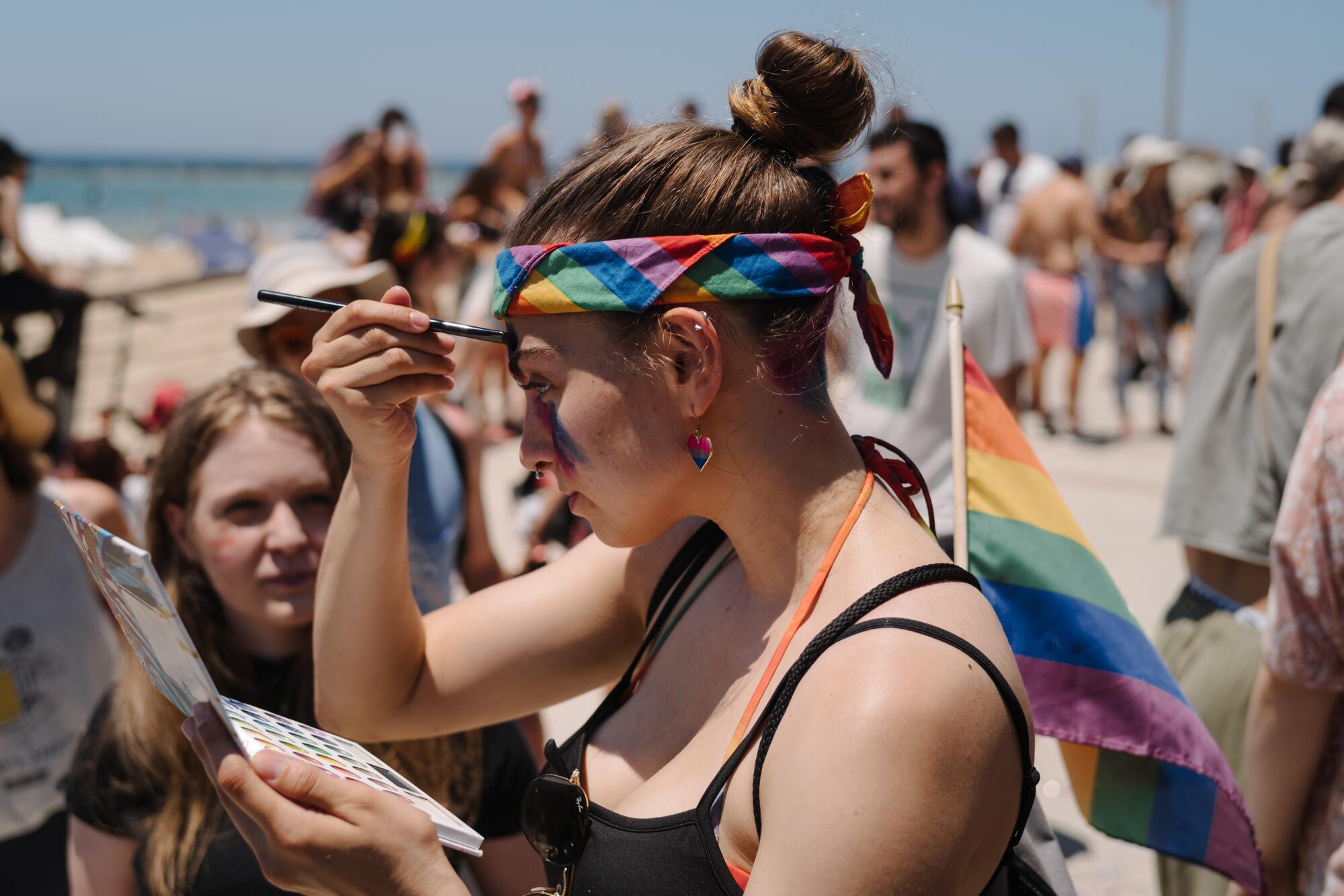 A woman paints her face near the beach. 