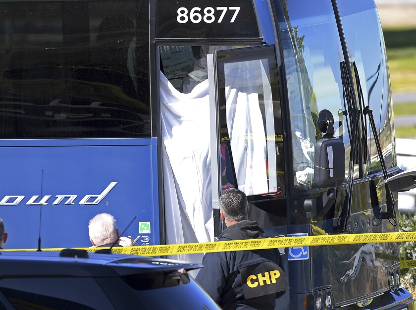 Coroner's officials work behind a drape to remove the body of a person who was killed when a gunman opened fire aboard a packed Greyhound bus, and wounded five others before the driver pulled over onto the shoulder and the killer got off, in Lebec, Calif., some 75 miles north of Los Angeles, Monday, Feb. 3, 2020. The suspect was taken into custody without incident, and authorities say the the motive is unknown. The bus was traveling from Los Angeles to San Francisco on Interstate 5 at the time of the shooting early Monday. (AP Photo/Jayne Kamin-Oncea)