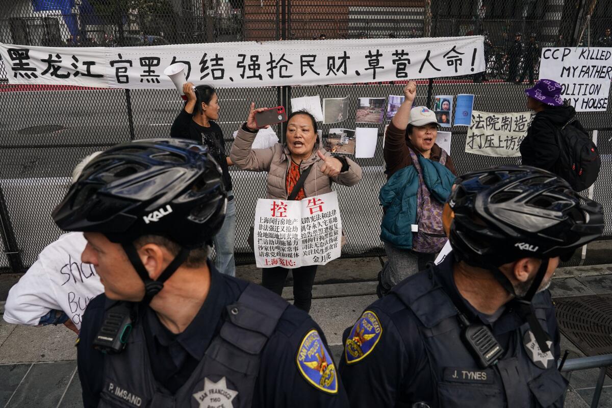 A few people hold signs and stand behind two police officers on a sidewalk.