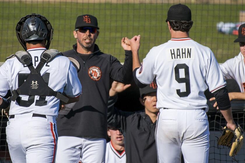 Huntington Beach's head coach Benji Medure congratulates Josh Hahn in the second inning during a game aginast Damien on Thursday, March 1.