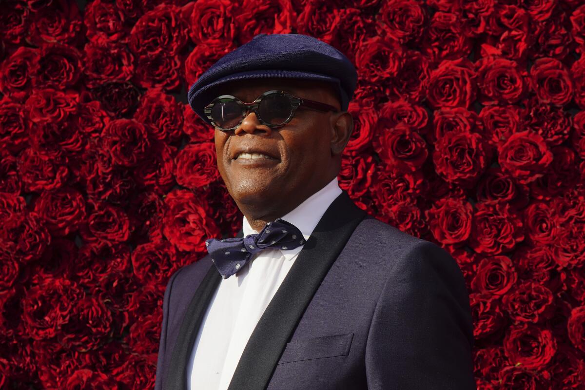 Samuel L. Jackson on a red carpet in a tuxedo and matching newsboy cap. 