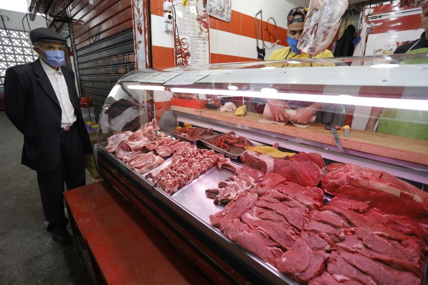 A man waits to buy meat at a market in Algiers, Tuesday April 21, 2020. Algerian are shopping to prepare the holy month of Ramadan which starts Thursday in Algeria. Muslims around the world are trying to maintain the cherished rituals of Islam holiest month without further spreading the coronavirus outbreak. (AP Photo/Toufik Doudou)