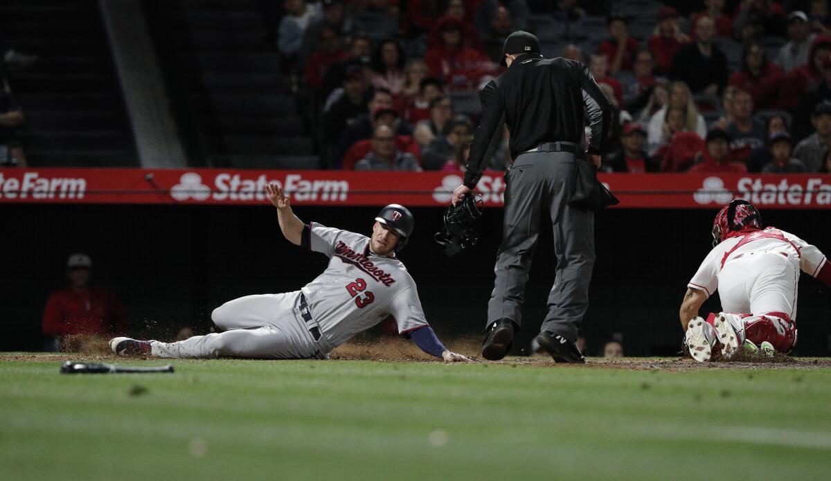 Minnesota Twins catcher Mitch Garver (23) scores as Los Angeles Angels catcher Rene Rivera waits for the throw in the 12th inning.
