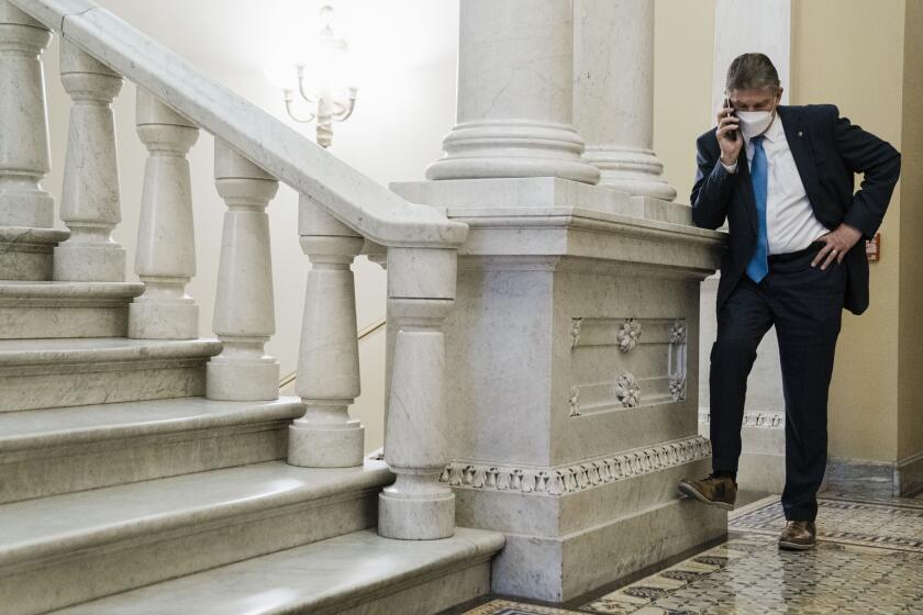 WASHINGTON, DC - JANUARY 19: Sen. Joe Manchin (D-WV) on a phone call in a hallway just outside the Senate Chamber, after speaking on the floor of the Senate, on Capitol Hill on Wednesday, Jan. 19, 2022 in Washington, DC. The Senate heads towards a vote on whether or not to enact sweeping voting rights reforms. (Kent Nishimura / Los Angeles Times)