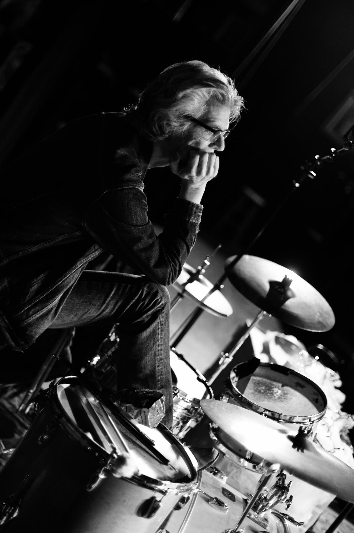 Don Heffington, behind his drum kit, leans his chin into his hand.