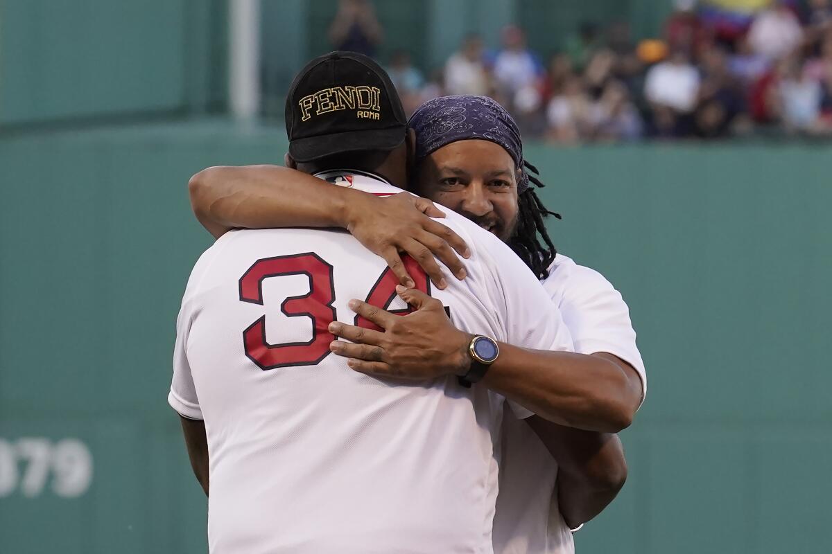 Former Boston Red Sox's Manny Ramirez, right, hugs former teammate David Ortiz (34) on the field during a pre-game ceremony held to present Ramirez with his Boston Red Sox Hall of Fame plaque before a baseball game against the Detroit Tigers, Monday, June 20, 2022, in Boston. (AP Photo/Steven Senne)