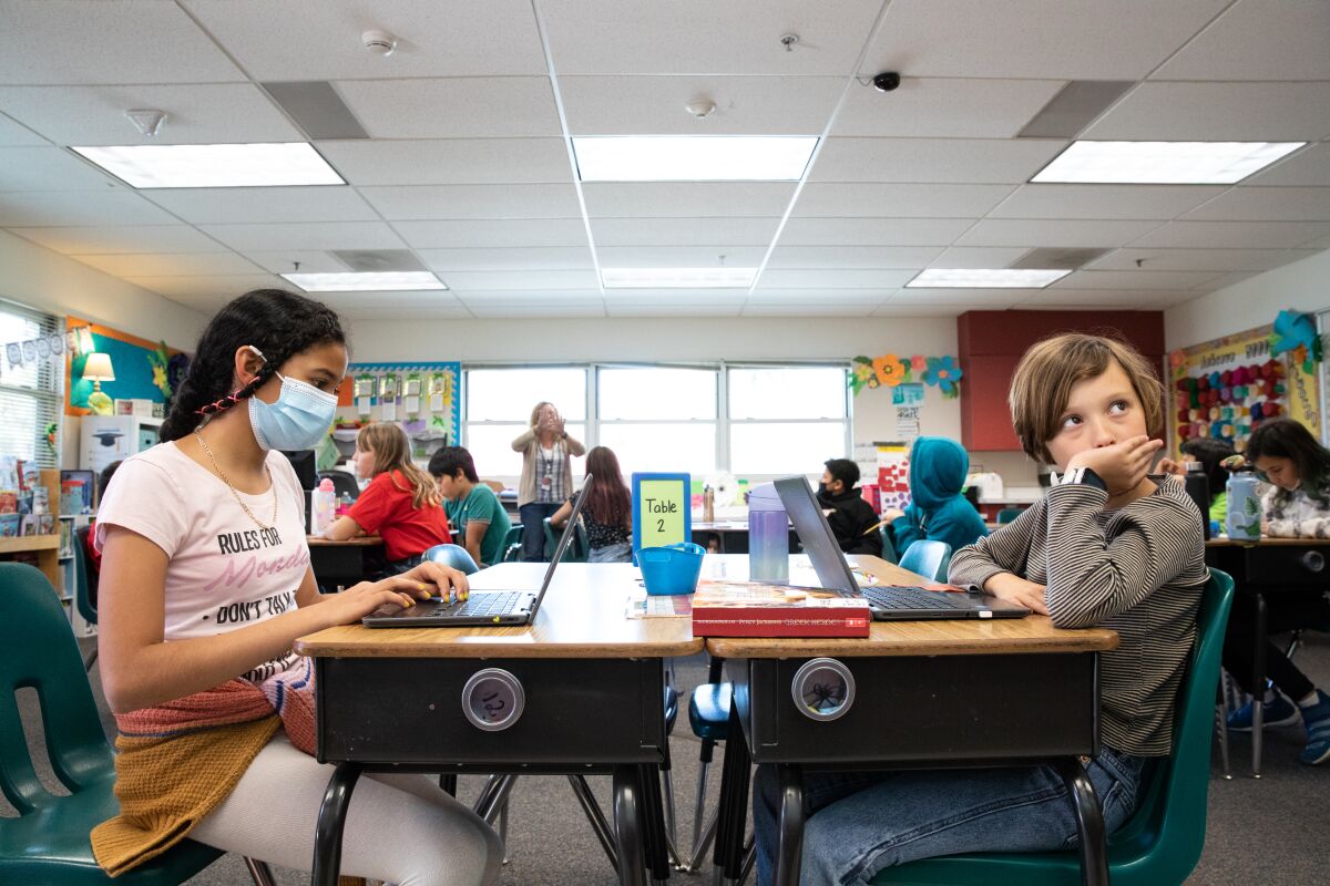Jada Carrillo wears a mask while Edie Gillen doesn't in science class at Calavera Hills Elementary in Carlsbad Monday.