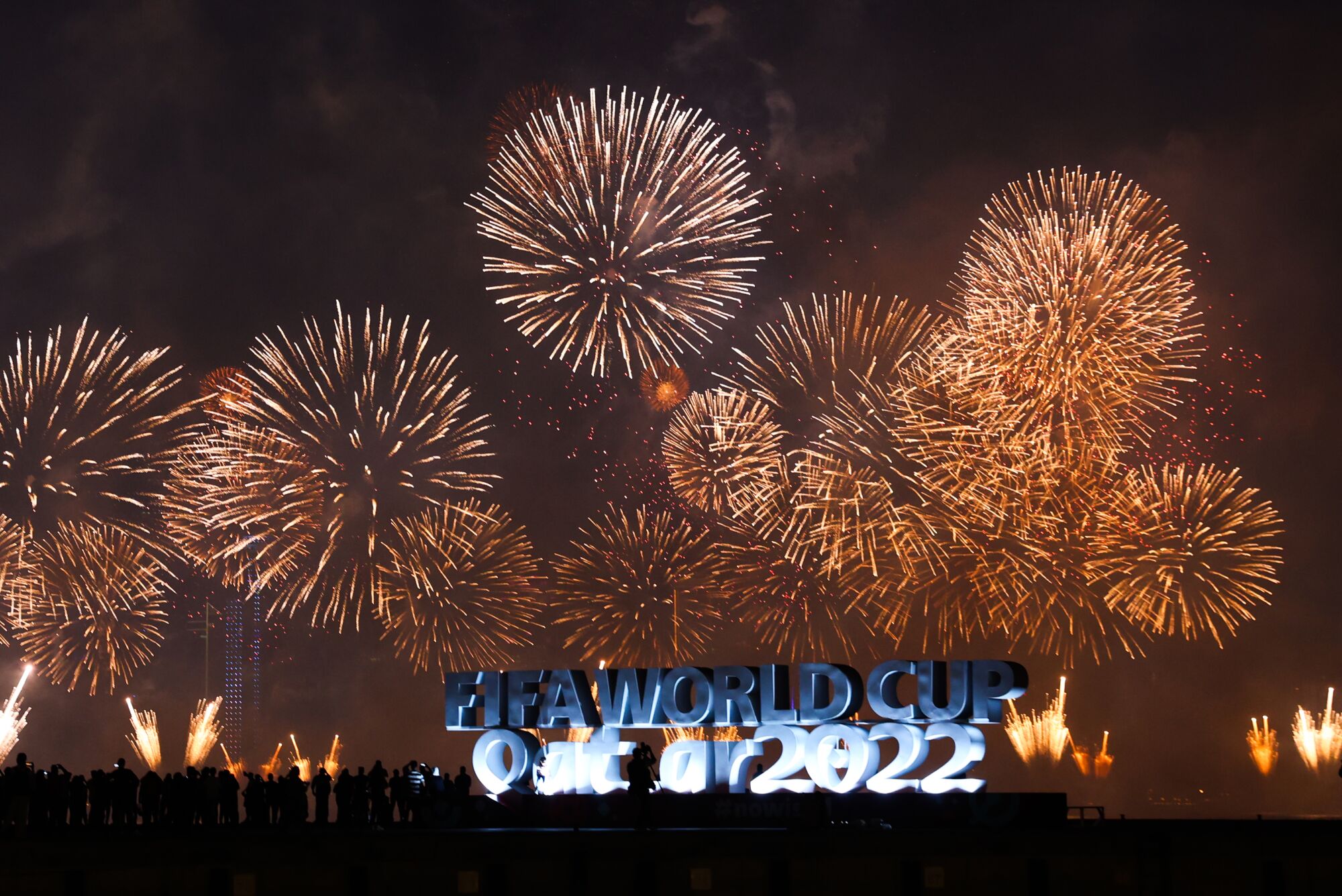 Fireworks explode above a sign promoting the 2022 World Cup in Qatar.