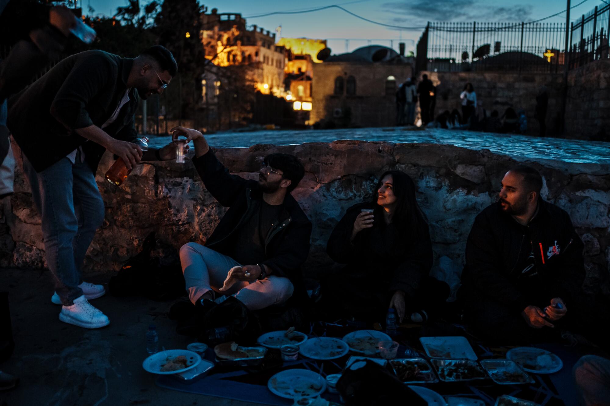 人们在屋顶上野餐，欣赏耶路撒冷老城圆顶清真寺的景色。