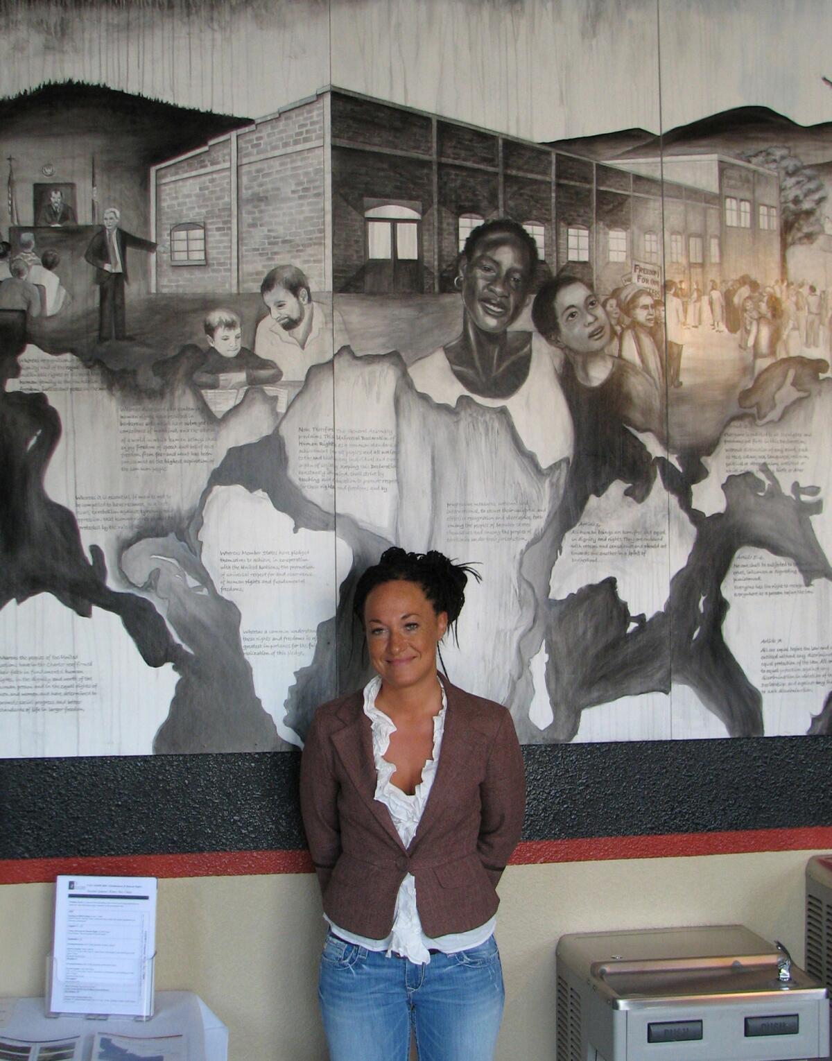En imagen del 24 de julio de 2009, Rachel Dolezal, una líder del Instituto de Educación en Derechos Humanos, posa frente a un mural que ella misma pintó en las oficinas del instituto en Coeur d'Alene, Idaho. Dolezal, ahora presidenta de la sección de la Asociación Nacional para el Progreso de la Gente de Raza Negra (NAACP) en Spokane, Washington, se encuentra en medio de la polémica por haber mentido sobre su raza y origen étnico.