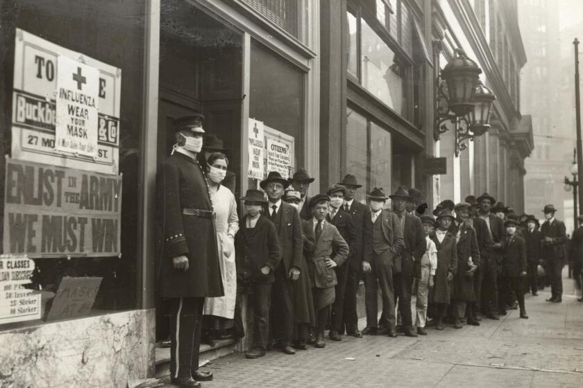 A handout picture provided by the California State Library shows people waiting in line to get flu masks on Montgomery Street in San Francisco, California, in 1918. Unlike Los Angeles, San Francisco stressed mask wearing, but not social distancing during the Spanish flu pandemic.