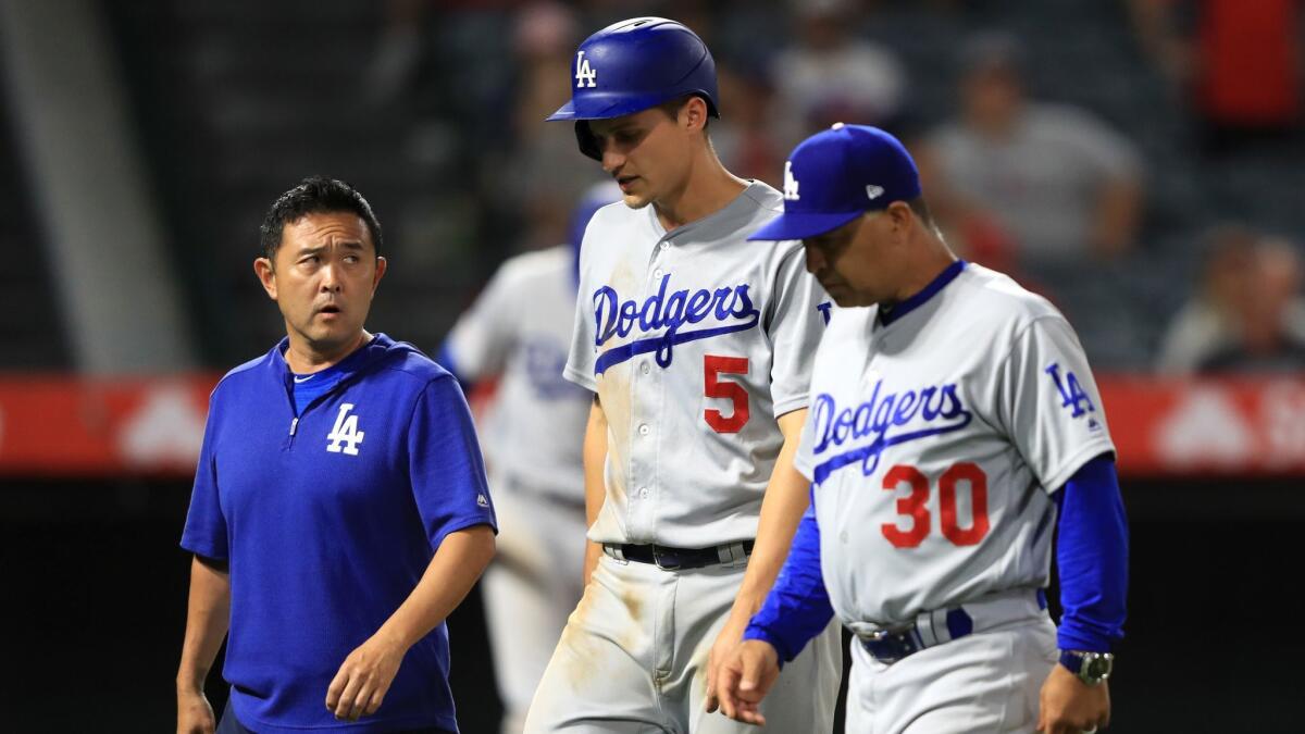 Dodgers manager Dave Roberts and a team trainer walk shortstop Corey Seager off the field after he suffered a hamstring injury June 12 against the Angels.