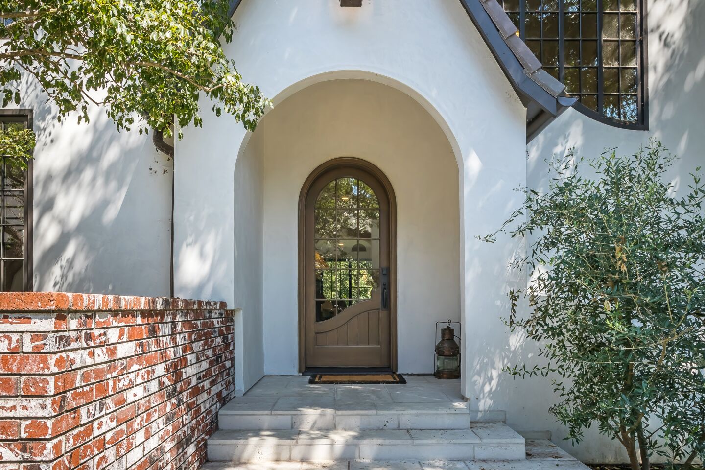An arched front door and pitched roofline lend a whimsical quality to the house.