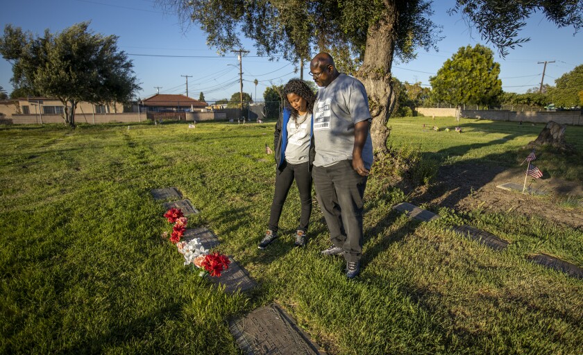A man and woman look at a row of grave markers.